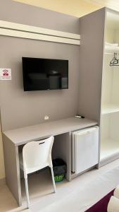 a desk with a tv on a wall with a chair at Villarejo Parque Hotel in Penha