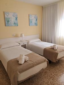 two beds in a hotel room with towels on them at Apartamentos Cala Llonga in Cala Llonga +21 photos