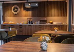 a restaurant with wooden tables and chairs and a counter at Hunzego Hotel in Uithuizermeeden