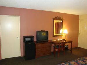 a hotel room with a television and a desk with a table at Wilmington Inn in Wilmington