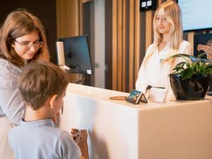 a young boy and a woman standing behind a counter with a girl at Novotel Lodz Centrum in Łódź