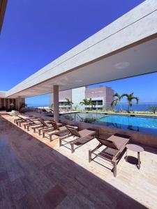 a group of lounge chairs and a swimming pool at Edificio Reserva del Mar Bello Horizonte in Playa Bello Horizonte