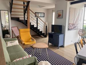 a living room with a couch and a tv and stairs at Maison vue mer Riantec in Riantec