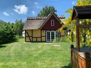 a small yellow and red house with a yard at Charmig stuga i Abbekås in Abbekås