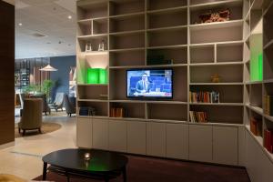 a living room with a tv and a book shelf at Elite Hotel Ideon, Lund in Lund