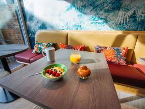 a table with a bowl of fruit and a bowl of orange juice at ibis Styles Antibes in Antibes