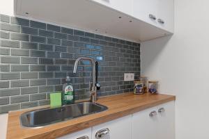 a kitchen with a sink and a gray tile wall at Ferienwohnung Tromei-Hof in Oberderdingen +12 photos