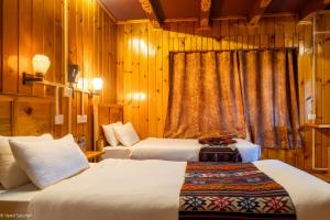 two beds in a room with wooden walls at Phuntsho Guest House in Jakar