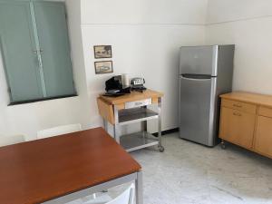 a kitchen with a refrigerator and a wooden table at Oliveto Sleeps 4 with Private Garden in Castelbianco