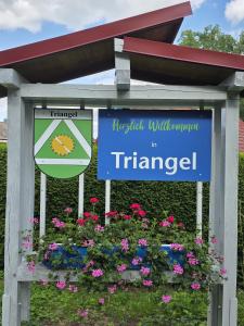 a sign in a flower bed with flowers at FeWo Weitblick in Sassenburg +17 photos