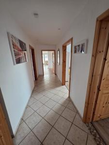 a hallway with white walls and a tile floor at FeWo Weitblick in Sassenburg