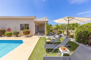 a villa with a swimming pool with chairs and an umbrella at Villa Sea Side in Polis Chrysochous
