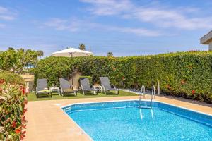a swimming pool with chairs and an umbrella in a yard at Villa Sea Side in Polis Chrysochous