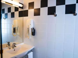 a bathroom with a sink and a phone on the wall at ibis Styles Bourbon Lancy in Bourbon-Lancy +42 photos