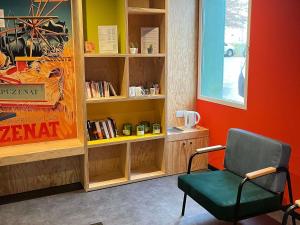 a room with a chair and a book shelf at ibis Styles Bourbon Lancy in Bourbon-Lancy
