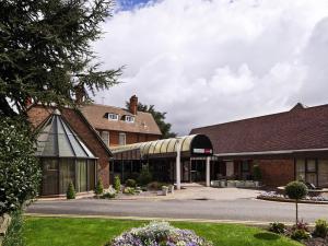 a large brick building with a conservatory in a yard at Mercure Hull Grange Park Hotel in Hull