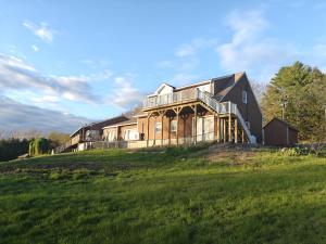 a large house on top of a grassy hill at Beautiful Bridgton Apartment in Bridgton