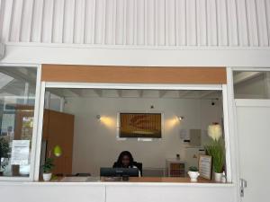 a woman sitting at a desk in an office at Cit'Hôtel du Parc in Carrières-sous-Poissy