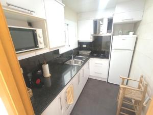 a kitchen with white cabinets and a black counter top at Seafront Sitges in Sitges