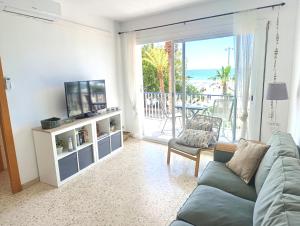 a living room with a couch and a tv and a balcony at Seafront Sitges in Sitges