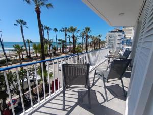 a balcony with chairs and a table and the beach at Seafront Sitges in Sitges