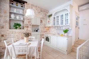 a kitchen with white cabinets and a table and chairs at Antica casa Scesciola in Rutigliano