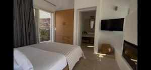 a bedroom with a white bed and a television at Gaia & Thalassa Villa Nafsika in Otziás