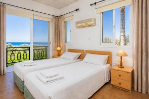 two beds in a room with two windows at Villa Sotiroula in Kato Yialia +12 photos