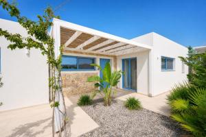 a white house with a tropical garden at Villa Pollux in Gennadi