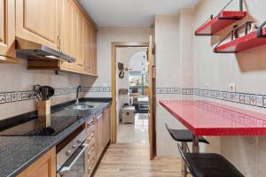 a kitchen with a red counter top and wooden cabinets at Piso La Alondra in Fuengirola