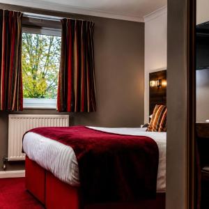 a bedroom with a bed with a red blanket and a window at The Gibside Hotel in Gateshead +66 photos