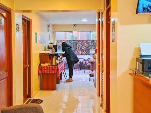 a woman is standing in a hallway with a table at Hawka Inka hotel cusco in Cusco