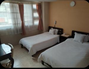 a hotel room with two beds and a window at Hotel Surandino Fátima in Pasto