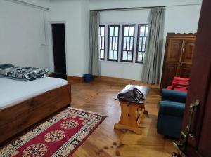 a bedroom with a bed and a chair and a rug at The Blooming Tulip in Shergaon