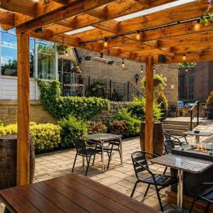 a patio with tables and chairs under a wooden pergola at The Gibside Hotel in Gateshead