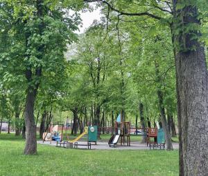 a park with a playground with benches and trees at KUBU namai in Klaipėda