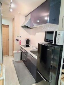 a kitchen with a black refrigerator and a sink at Hachi Kamakura KOIWA in Tokyo