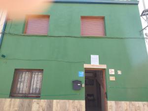 a green building with two windows and a door at CASA GORDON in Navaluenga