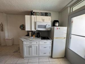 a kitchen with white cabinets and a white refrigerator at Direct ocean front view 1 bedroom 2 Pools in Daytona Beach