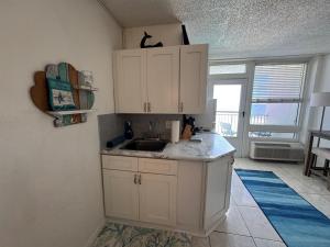 a kitchen with white cabinets and a sink at Direct ocean front view 1 bedroom 2 Pools in Daytona Beach