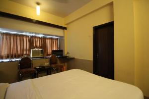 a bedroom with a bed and a desk and a window at HOTEL GOLDEN PALACE PVT LTD in Mumbai +4 photos