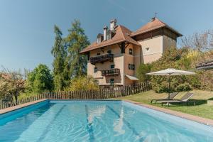a house with a swimming pool in front of a building at Villa Maier B&B & Apartments in Soprabolzano