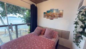 a bedroom with a bed with a view of the ocean at Suítes Recanto dos papagaios in Angra dos Reis