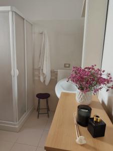 a bathroom with a table with a vase of flowers on it at Passo lento in Leverano +22 photos
