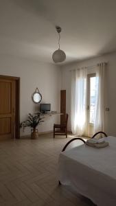 a white room with a bed and a television at Passo lento in Leverano