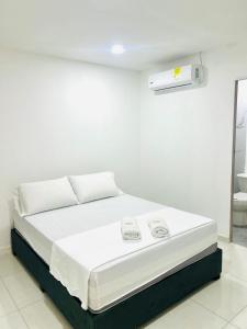 a white bed in a room with a white wall at Hotel Galicia in Montería