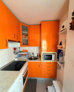 a small kitchen with orange cabinets and a sink at Apartamento Liencres in Liencres