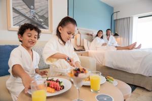 a boy and a girl eating food in a hotel room at Dreams Aventuras Riviera Maya - All Inclusive in Puerto Aventuras