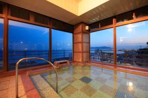 a balcony with a hot tub in a building with windows at Heiseikan Kaiyotei in Hakodate