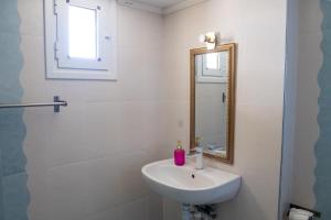 a white bathroom with a sink and a mirror at Maria Apartments in Perea +8 photos